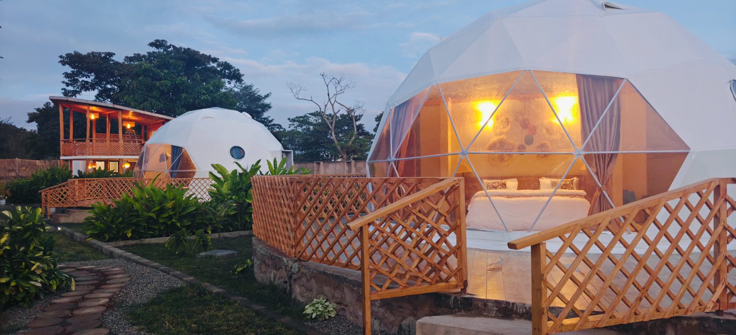A glowing dome at twilight, bed framed by the geodesic window